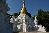 Myanmar - Inwa, white washed stupas with a Buddha statue protected by a naga where the road branch off to the teack monastery.